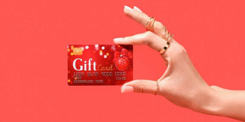Woman's hand holding a red gift card.