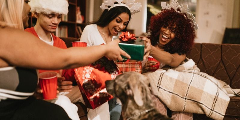 group of friends exchanging holiday gifts wearing snowflake headbands