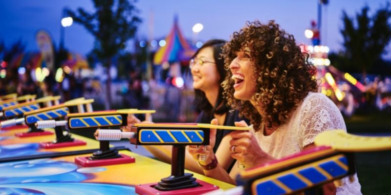 Two young women having fun and playing games at a summer carnival