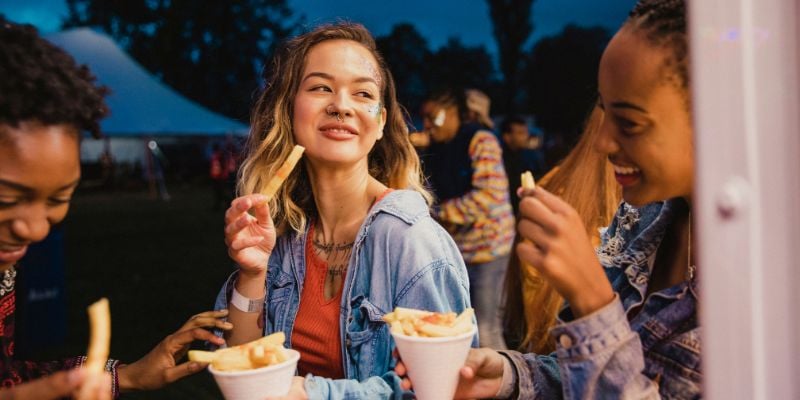 Small group of friends sharing portions of chips at a festival