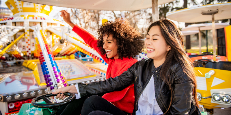 Two woman laughing and smiling while riding on an amusement park ride