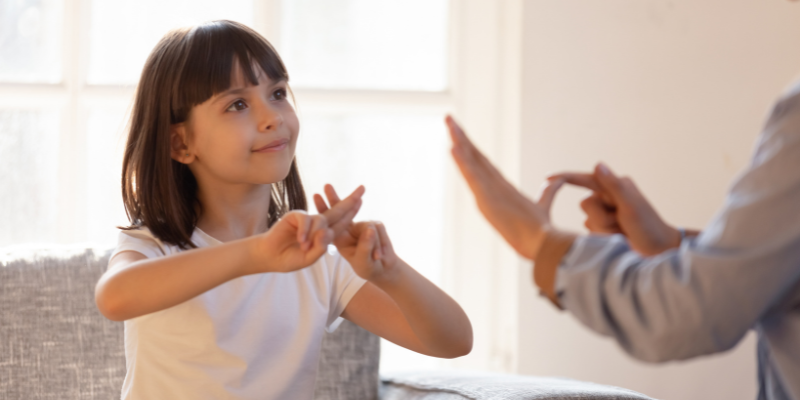 Young girl practicing sign language with parent