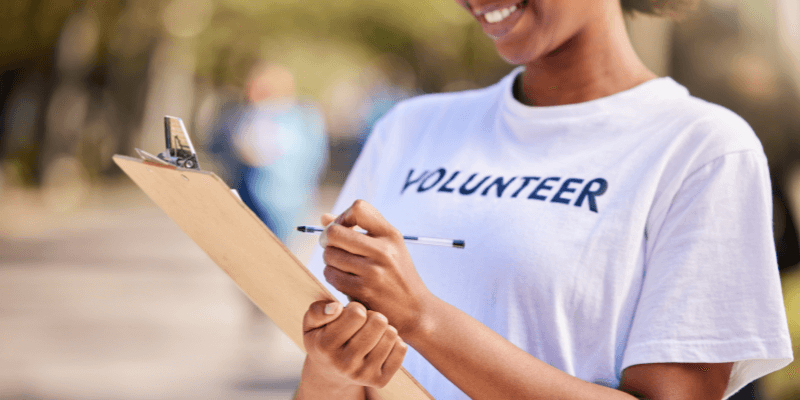 A close-up of a woman smiling and writing on a clipboard while volunteering. (1)