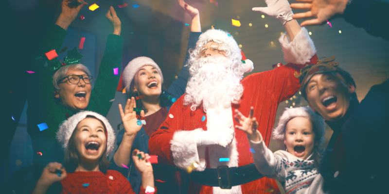 A family with Santa Claus, throwing confetti into the air and smiling.