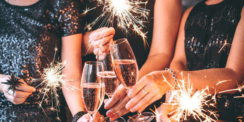 Three people cheersing champagne flutes with sparklers.