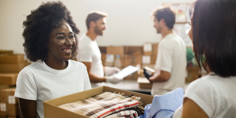 Woman smiling while handing over a box of clothes.