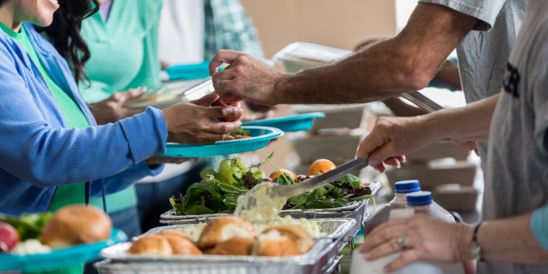 Close-up of hands passing out food at a donation center.