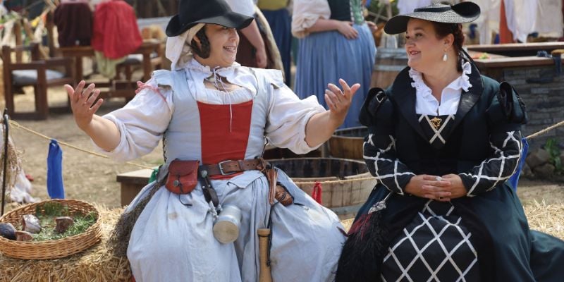 two women seating and talking in costume at a renaissance fair