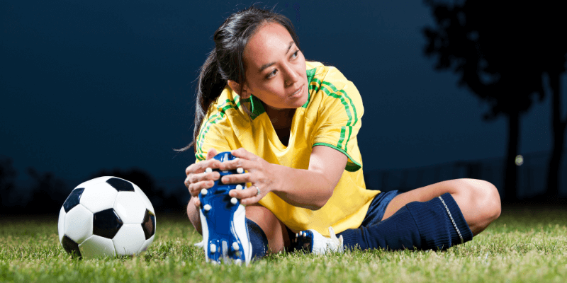 Woman stretching while getting ready to play soccer.  (1)