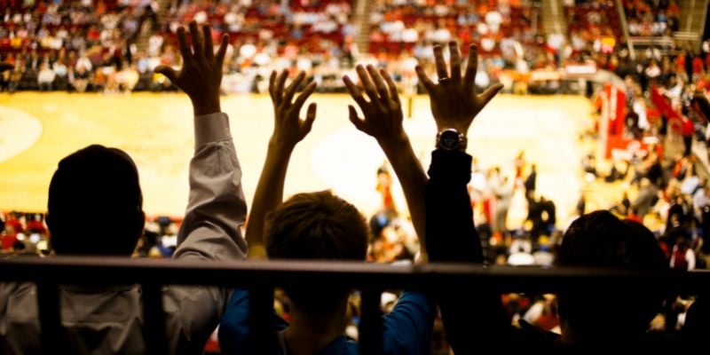 fans waving their hands in the air while watching a basketball game in a stadium