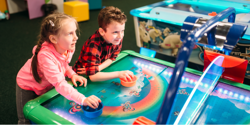 Little kids plays air hockey, entertainment center