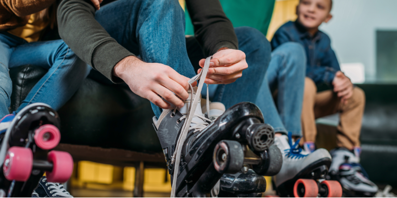 Partial view of man tying shoelaces on roller skate