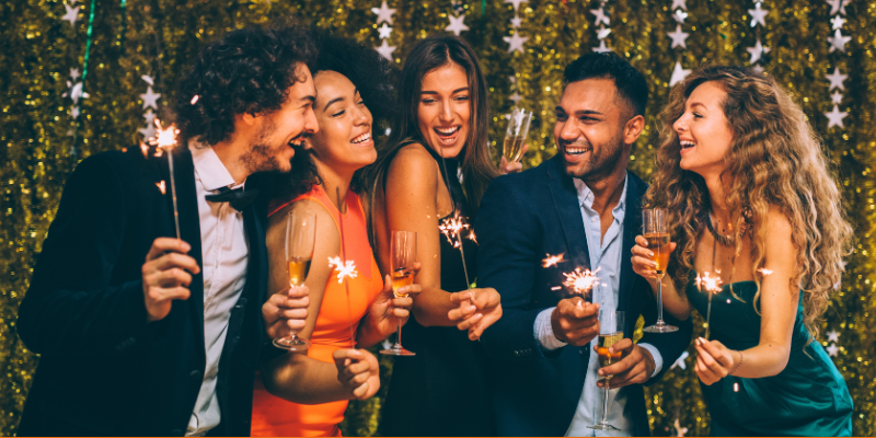 Friends toasting with champagne and playing with sparklers at New Years Eve party