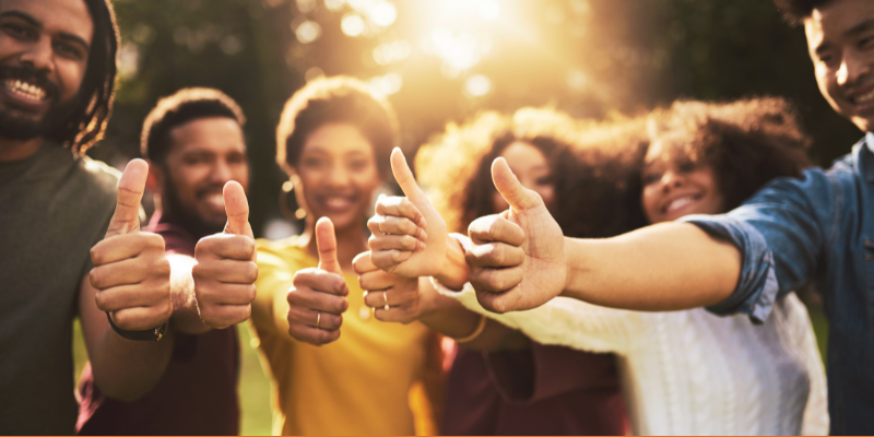 Group of friends showing thumbs up outdoors on a sunny day