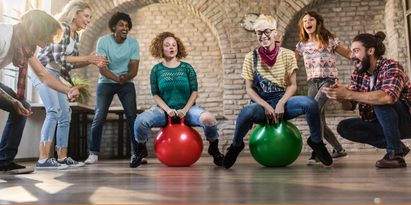 Group of employees having fun during hoppity horse race in the office