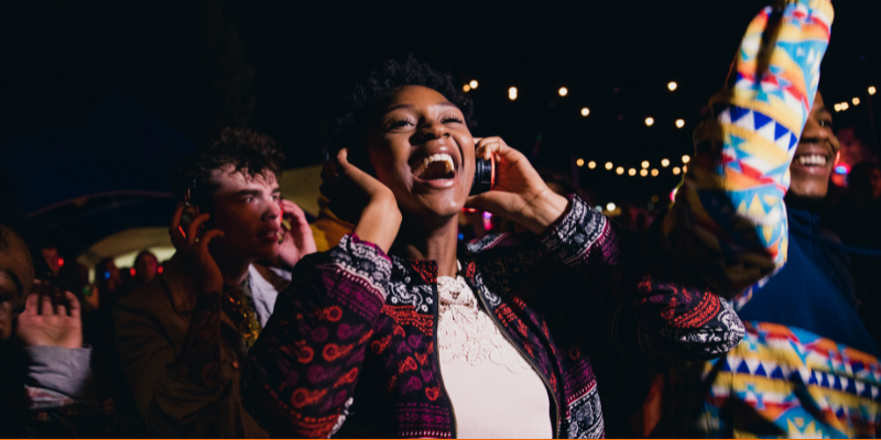 Young woman singing and dancing at a silent disco with friends