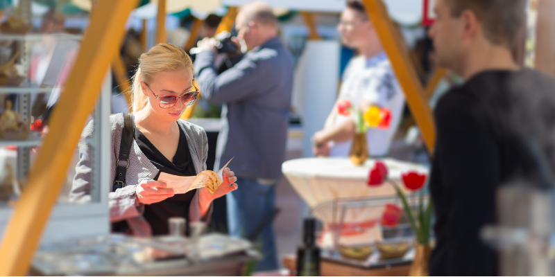 Woman buying freshly prepared meal while reviewing the menu at a local street fair
