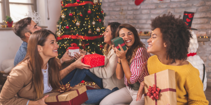 Group of friends having fun while exchanging Christmas gifts at home