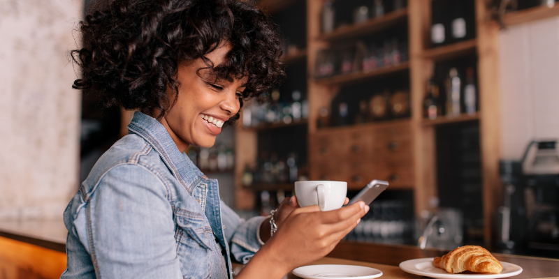 Smiling woman using smartphone in a modern cafe