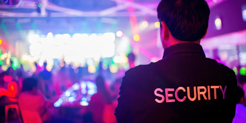 Security guard viewed from behind watching over a concert event at a nightclub