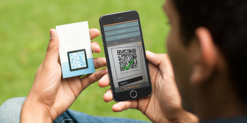 Young man seen from behind holding up a smartphone with Passage Manager app open to scan a QR code ticket