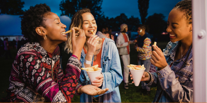 Small group of friends sharing portions of French fries at a festival