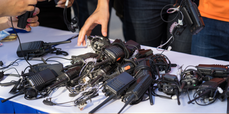 Portable walkie-talkies on a table with hands picking up devices for use