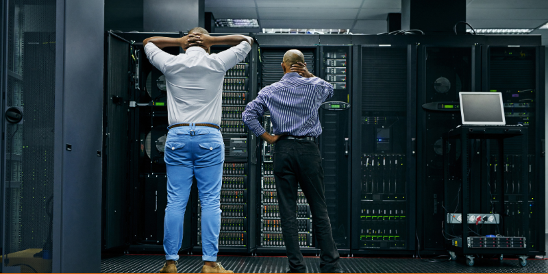 Rearview of two technicians having trouble with a computer server at work