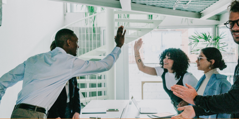 Corporate team giving high fives across a conference room table