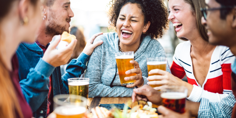Multiracial friends laughing and drinking beer and an outdoor beer garden