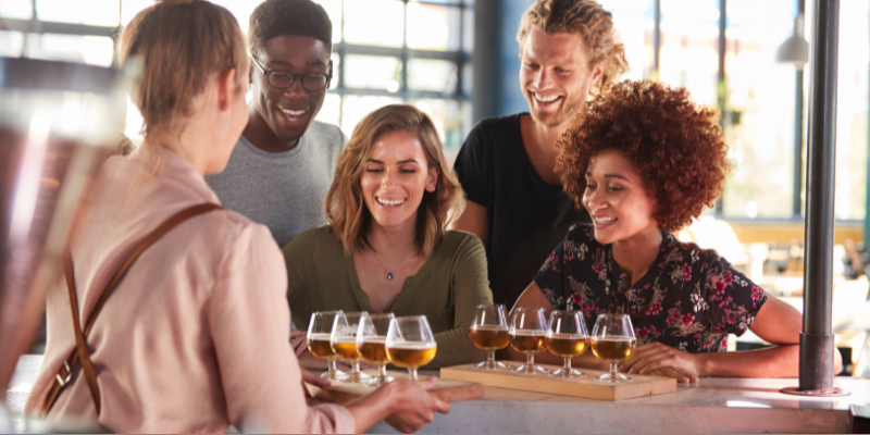 Bartender serving a group of friends a beer flight at a brewery