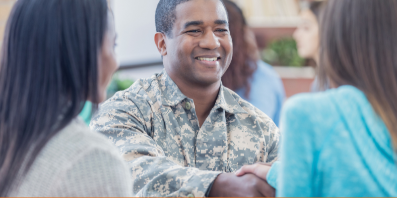 Cheerful African American Marine greets people at a networking event