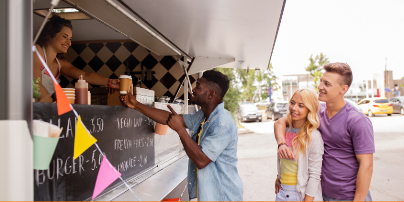 Happy customers queuing up at a food truck serving burgers and vegan wraps
