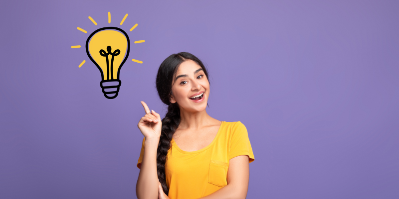 Woman in yellow shirt thinking of a great idea while pointing at a lightbulb drawn on purple background