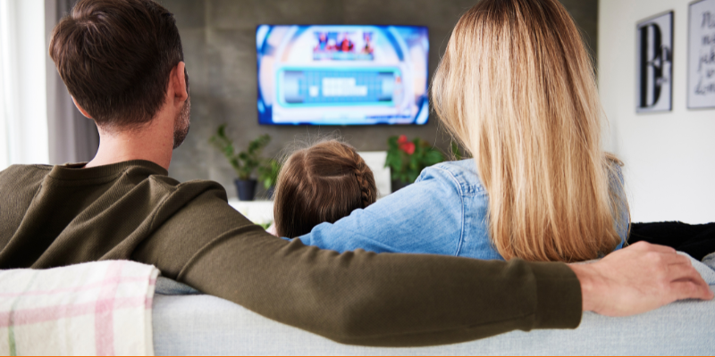 Rear view of family watching TV at home