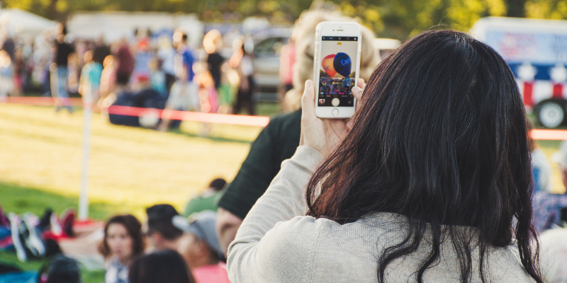 Woman taking a photo on her phone at a hot air balloon festival
