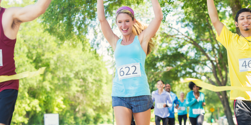 Runners breaking through the finish line ribbon at an outdoor race