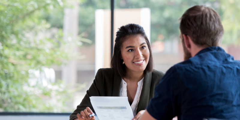 Businesswoman smiling while showing a document to a male colleague