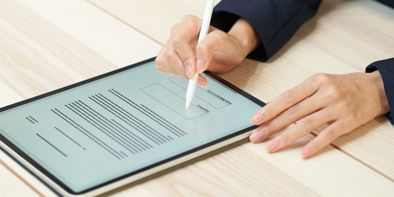 Close-up shot of hands signing a liability waiver on a tablet screen