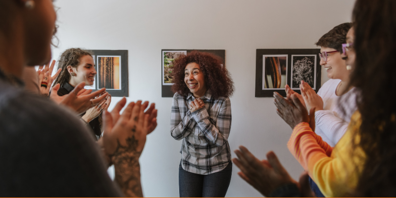 Friends clapping and celebrating a woman at her art exhibition