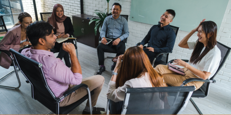 Multiracial group of people sitting in a circle and having a meeting in a modern office