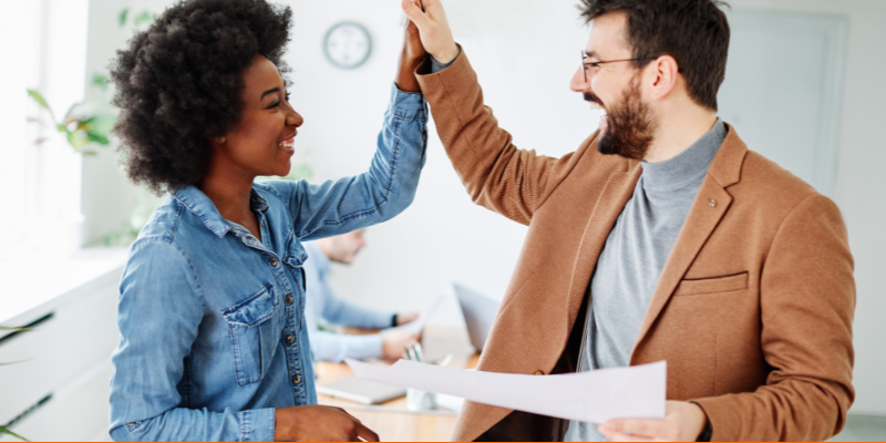 Pair of happy young business people high fiving in the office