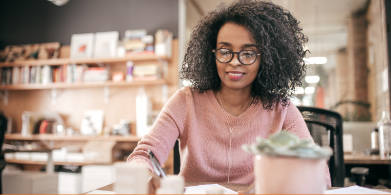 Woman in pink sweater in a modern office calculating her budget