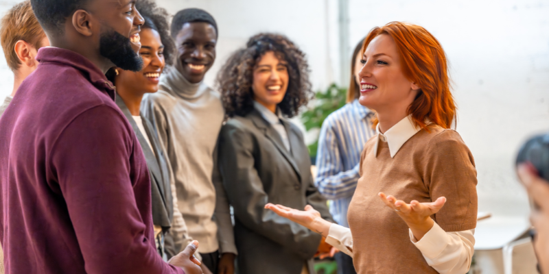 The Social Butterfly_ new member of working team presenting herself to diverse colleagues in the office