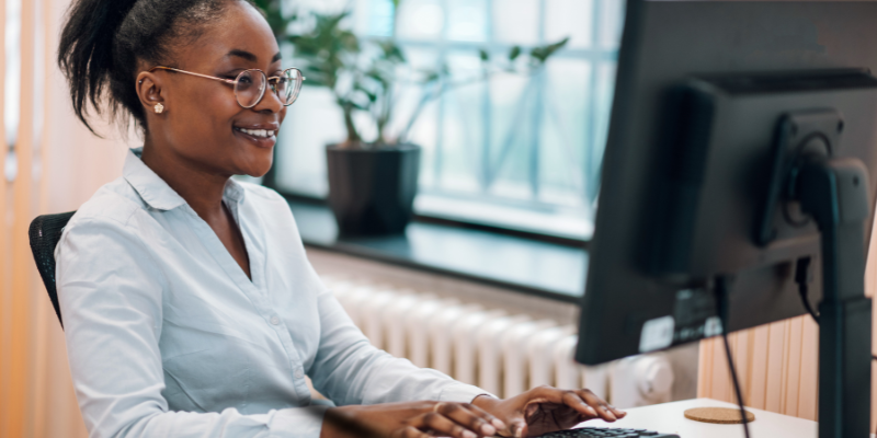 The Spreadsheet Guru_ smiling young woman in business casual attire working at a desktop computer