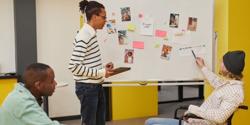 The Vibe Curator_ three team members looking at a whiteboard with inspiration photos