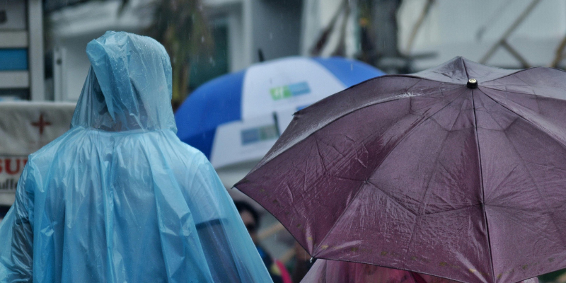People walking in the rain with ponchos and umbrellas