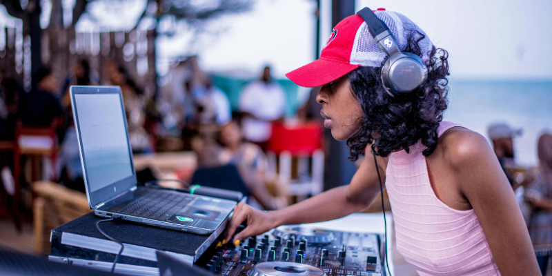 Woman playing DJ turntable at an outdoor beach club