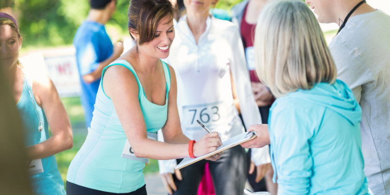 Woman signing name on clipboard to register for charity run