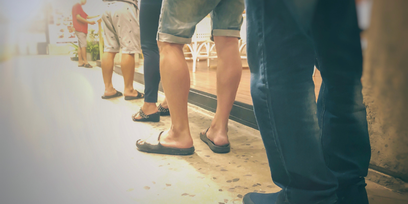 Row of people in a queue waiting to enter, viewed from behind